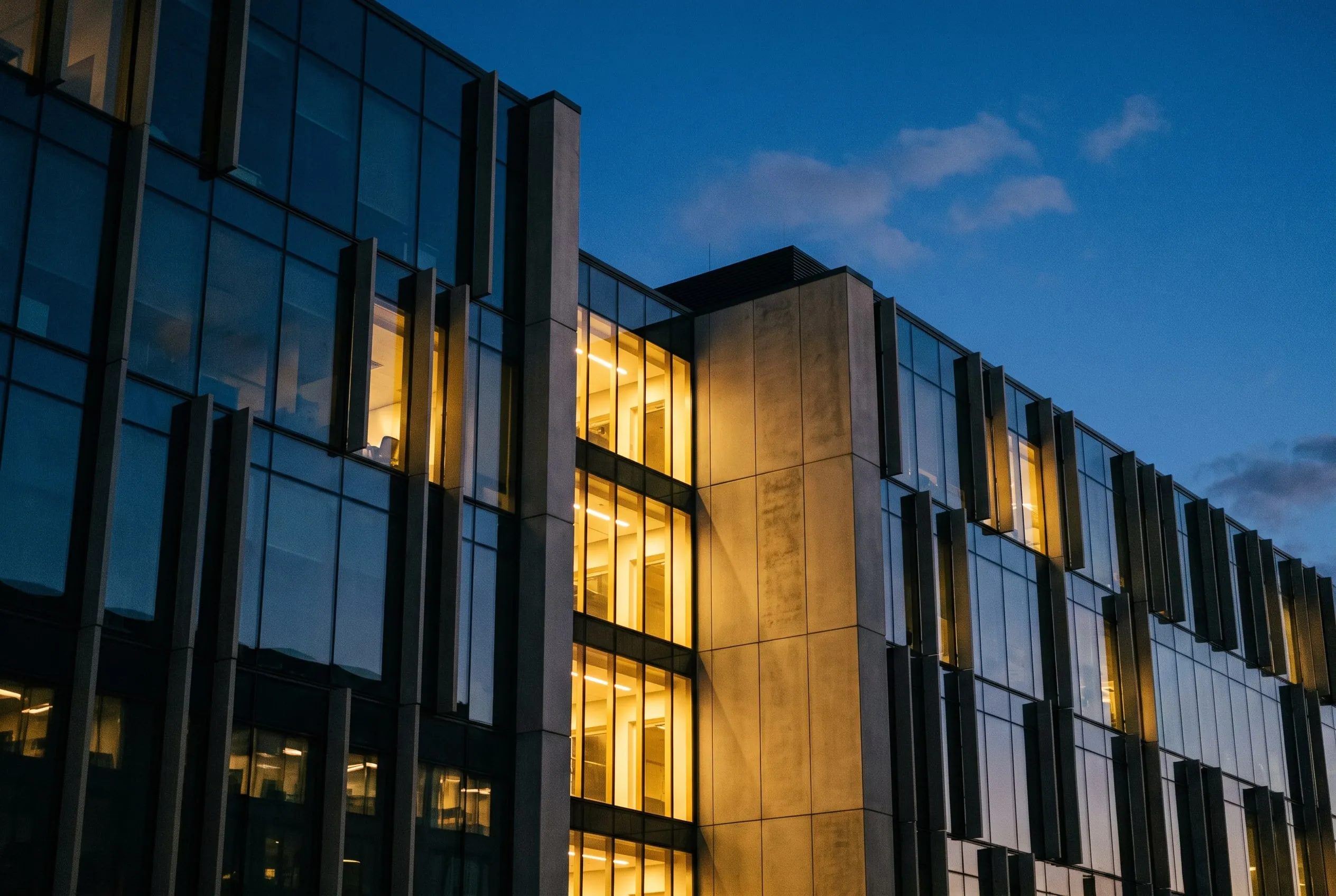 Illustrative: glass office facade at blue hour